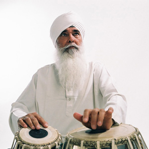 the late gurmit singh virdee, dressed in white kurta and turban, playing tabla